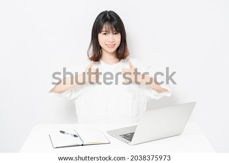 A young woman making a like gesture while using a laptop