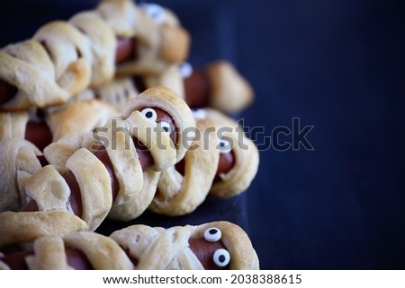Fun food for kids. Group of mummy hot dogs on a blue rustic table. Selective focus with blurred foreground and background. 