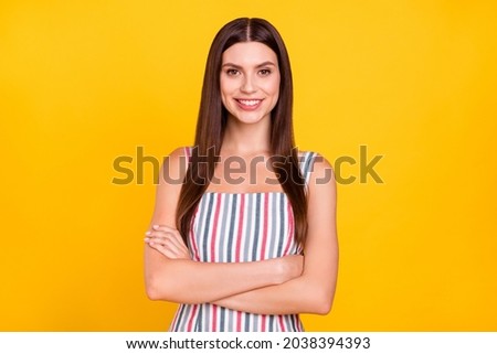 Photo portrait woman smiling with crossed hands confident in striped dress isolated vivid yellow color background