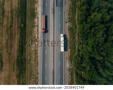 Two trucks driving on Highway along the fields. Aerial view landscape. Cargo delivery
