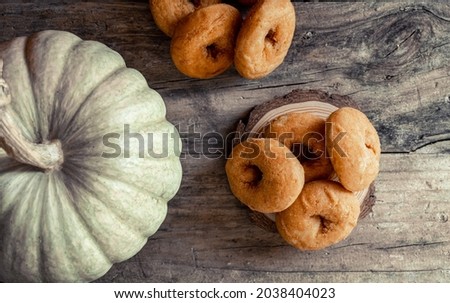 Homemade pumpkin donuts, a typical autumn sweet, on a rustic wooden background. 
