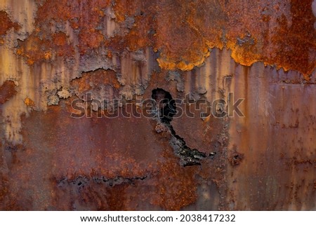 Rust of metals.Corrosive Rust on old iron with a hole. Rusted orange painted metal wall. Rusty metal background with streaks of rust. Old shabby paint.metal rust texture background Royalty-Free Stock Photo #2038417232