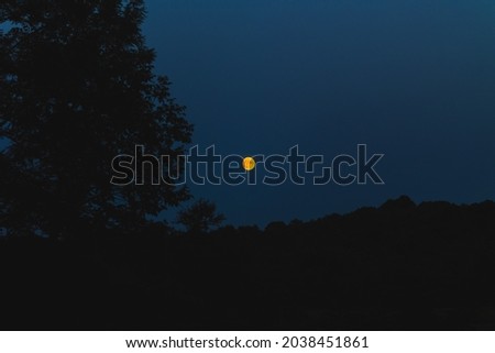 Orange moon seen from the countryside at evening at summer