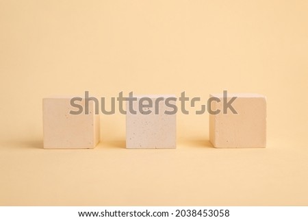 Three concrete cubes on a beige abstract background. geometric podium. Empty showcase for the presentation of cosmetic products.