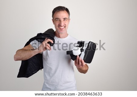 Man showing virtual reality headset dressed in white t-shirt on white isolated background