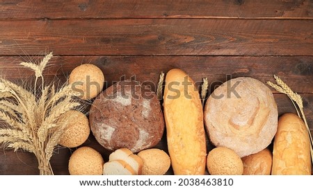 Assortment of homemade sourdough bread with crispy crust and ears of rye and wheat on an old wooden background with place for text, modern bakery concept, top view, healthy natural food