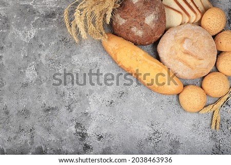 Assortment of homemade sourdough bread with crispy crust and ears of rye and wheat on gray concrete background with place for text, modern bakery concept, top view, healthy natural food, 