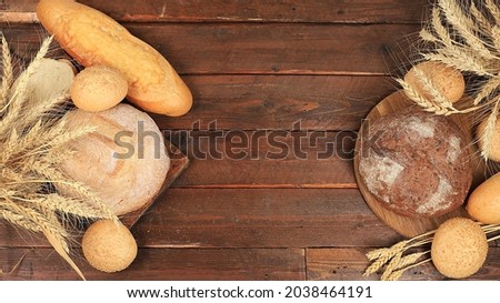 Freshly baked homemade sourdough bread with crispy crust and ears of rye and wheat on an old wooden background with place for text, modern bakery concept, top view, healthy natural food,