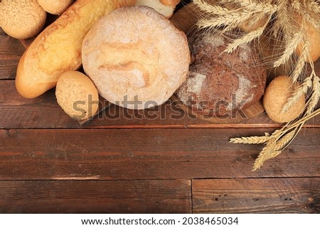 Freshly baked homemade sourdough bread with crispy crust and ears of rye and wheat on an old wooden background with place for text, modern bakery concept, top view, healthy natural food,
