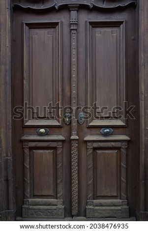 Background of a dark brown historical door with wooden decorations, which is made of wood