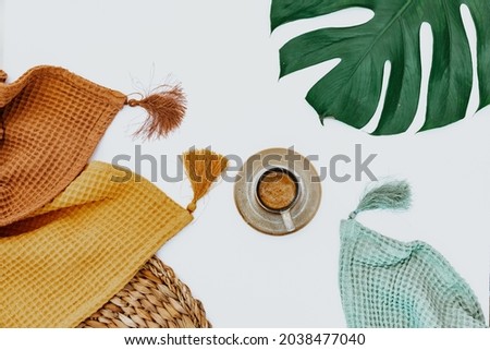 Two blankets, coffee cup and monstera leaf on white background, minimal simple background, workspace