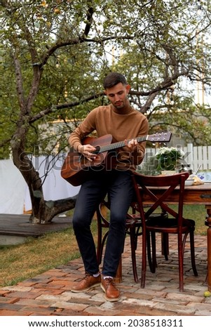 young man sits at the table and plays the guitar