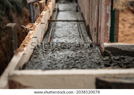 Timber formwork with metal reinforcement for pouring concrete and creating a solid foundation for a building or fence. Construction process. Royalty-Free Stock Photo #2038520078