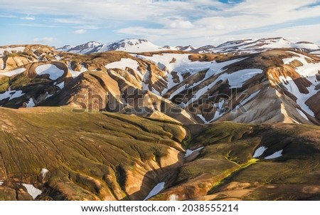 Folded mountain slopes covered with patches of snow in Landmannalaugar. 
