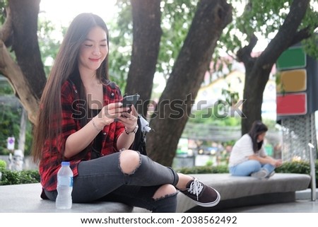 Cheerful woman using smart phone while sitting at outdoor.