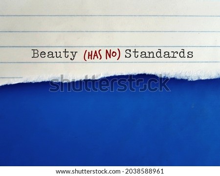 Torn note paper on blue copy space background with text BEAUTY HAS NO STANDARDS, concept of rebel against standard of beauty set by society, no more unrealistic beauty standard, everyone is beautiful