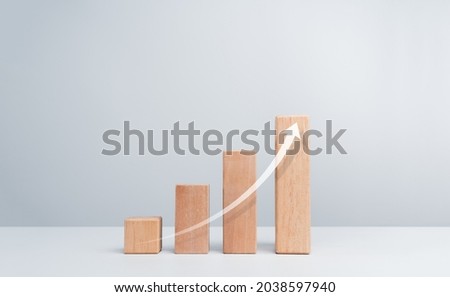 Rise up arrow on wooden blocks chart steps on a white clean background with copy space, minimal style. The business growth process, and economic improvement concept.