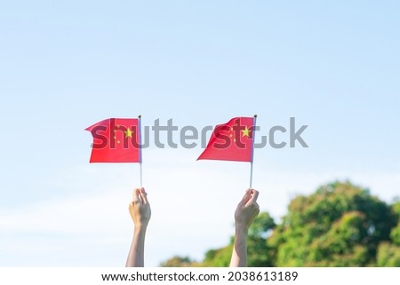 hand holding China flag on blue sky background. National Day of the People Republic of China, public Nation holiday Day and happy celebration concepts