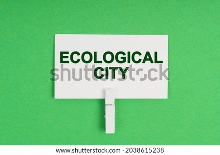 Ecology concept. On a green background, a business card on a clothespin. The business card says - Ecological City