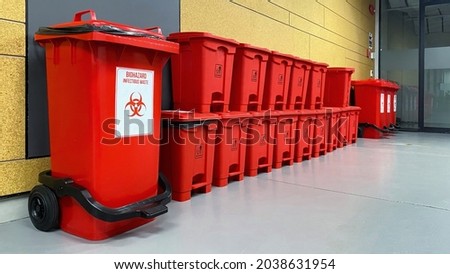 Stack of biological biohazard infected red bins. Sign showing the biological hazard symbol.