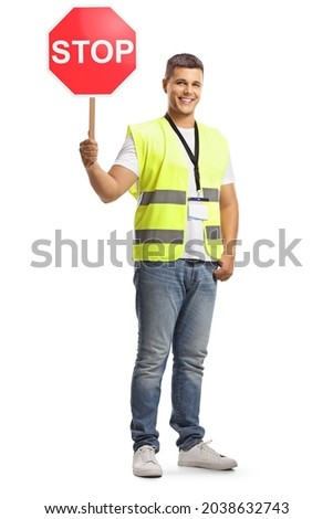 Young man in a safety vest with a stop traffic sign looking at camera and smiling isolated on white background