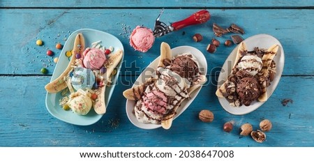 From above of row of plates with fresh banana slices and scoops of ice cream with different flavor served on blue wooden table Royalty-Free Stock Photo #2038647008