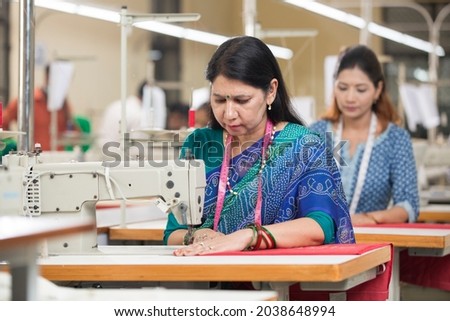 Indian woman textile worker using sewing machine on production line Royalty-Free Stock Photo #2038648994