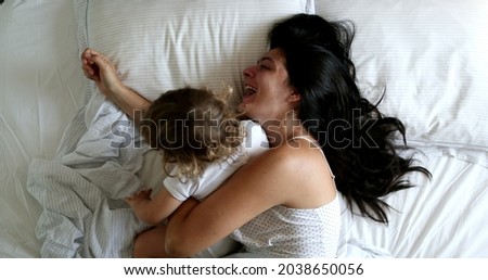 Mother waking up in the morning, baby getting in bed with mom. Mom infant love and affection