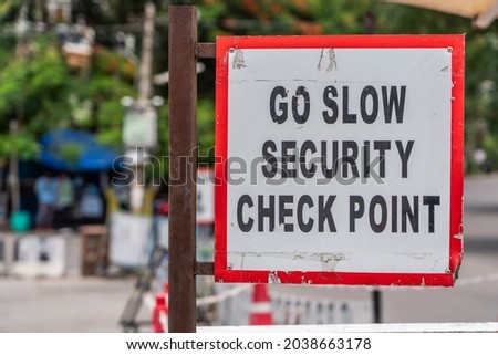 warning sign: "GO SLOW SECURITY CHECK POINT" with red frame, black letters on white background somewhere in a city 