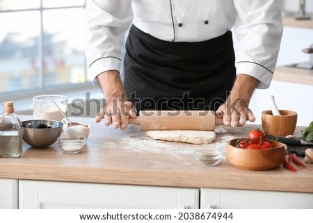 Mature male chef making dough for pizza in kitchen