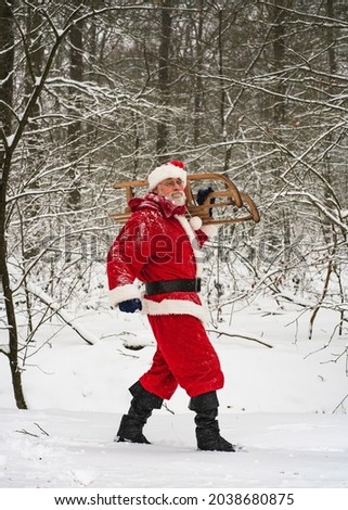 Winter holiday. Santa Claus in a traditional red costume walking with a sleigh in a snowy woods. The vital life range.