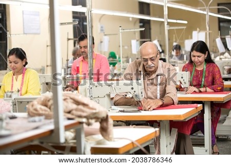Indian man sewing clothes with sewing machine at textile factory Royalty-Free Stock Photo #2038786346