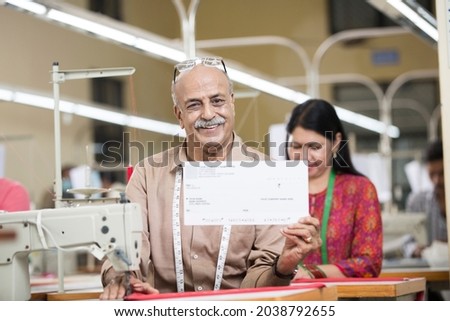 Senior man showing company paycheck at textile factory