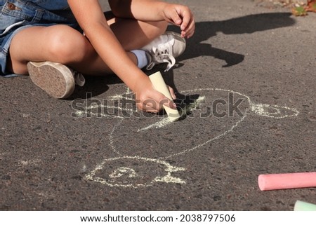 Little child drawing cat with colorful chalk on asphalt, closeup