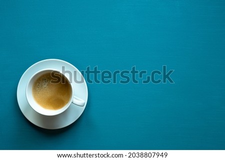 black coffee in a white cup, turquoise background, canvas texture, place for text, photo from above