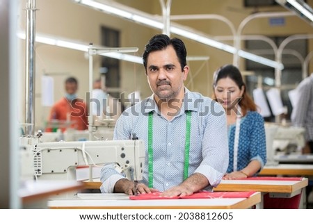 Man sewing clothes with sewing machine at textile factory
