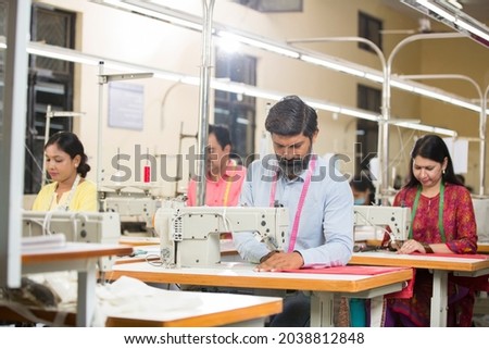 Man sewing clothes with sewing machine at textile factory Royalty-Free Stock Photo #2038812848