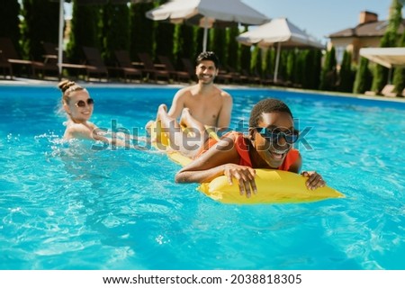 Cheerful friends swim on a mattress in the pool