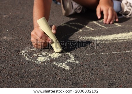Little child drawing cat with colorful chalk on asphalt, closeup