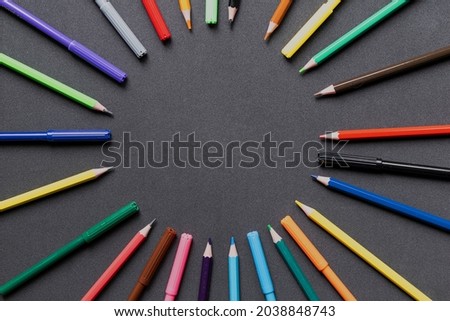A rainbow of colored pencils, on a dark background.