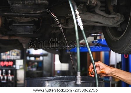 Auto mechanic loosen automatic transmission oil drain plug and then let the old used transmission oil drain out of the oil pan flange. Royalty-Free Stock Photo #2038862756