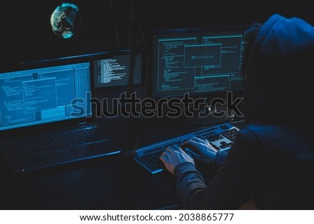 Cyber criminal hacking system at monitors, hacker attack web servers in dark room at computer with monitors sending virus using email vulneraility. Internet crime, hacking and malware concept.  Royalty-Free Stock Photo #2038865777