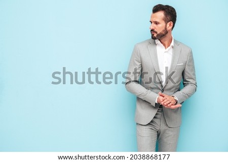 Portrait of handsome confident stylish hipster lambersexual model.Sexy modern man dressed in elegant suit. Fashion male posing in studio near blue wall. Royalty-Free Stock Photo #2038868177