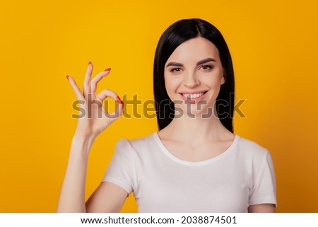 Portrait of attractive cheerful girl showing ok-sign ad solution isolated over bright yellow color background