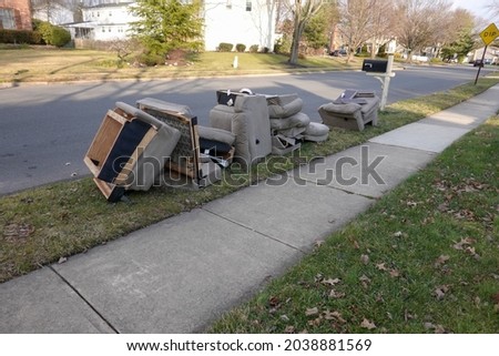 Old disassembled chairs and cushions lined up by the curb waiting to be disposed of by the garbage men on trash day Royalty-Free Stock Photo #2038881569