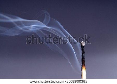 Smoke coming from an extinguished match against a dark purple background Royalty-Free Stock Photo #2038900385