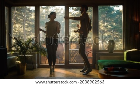 Happy Young Couple Dances in the Living Room. Cheerful Girlfriend and Boyfriend Enjoy True Love, Good Mood and Energetic Music Have Fun at Home. Stylish Interior and Sunny Day Royalty-Free Stock Photo #2038902563