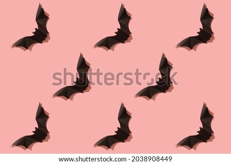 Black paper bat on a pink background. Halloween concept. With a hard black shadow. View from above.