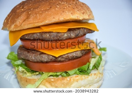 close up of double cheeseburger with cheddar cheese served on plate