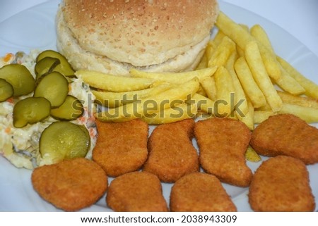 Top view of nugget plate with french fries, lettuce, tomato, pickled cucumber, american, russian salad
